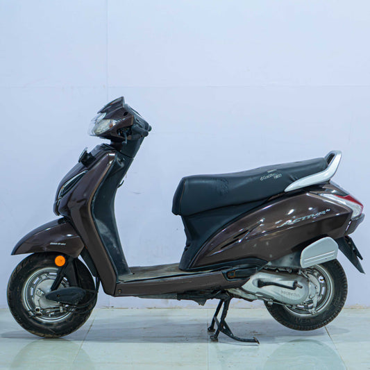 Honda Activa 5G scooter in a sleek design with black body and silver accents, displayed from a side view.