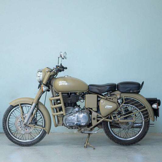 Royal Enfield Classic 500 motorcycle parked outdoors with chrome accents and vintage styling.