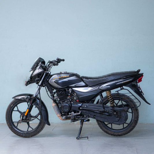 Bajaj Platina motorcycle with black and silver body, front view, showcasing sleek design and headlamp.
