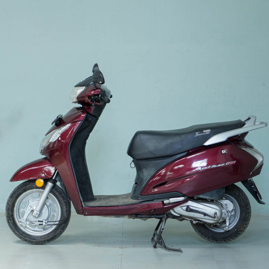Honda Activa 125 scooter with black seat and silver body, parked on a city street, showcasing the BikeDilwado model.