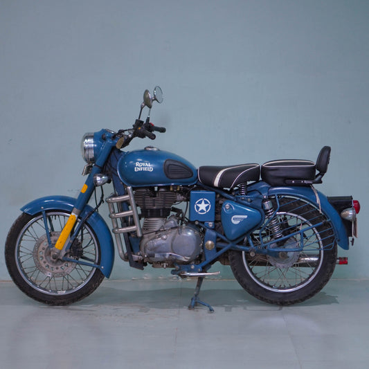 Royal Enfield Classic 500 motorcycle with chrome accents and vintage styling, shown from the side with detailed engine and black seat.