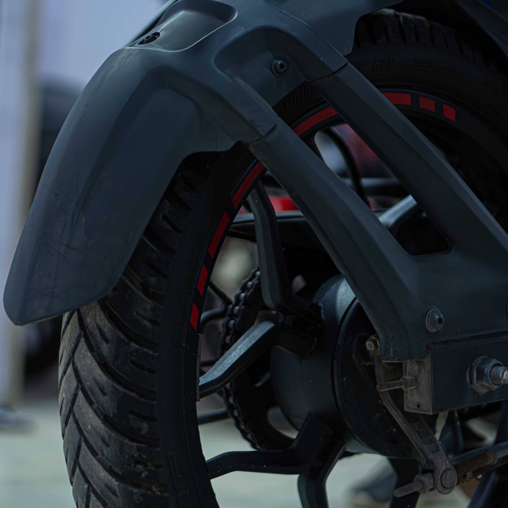 Red Bajaj NS 160 motorcycle with sleek design and sporty features, parked on a city street.
