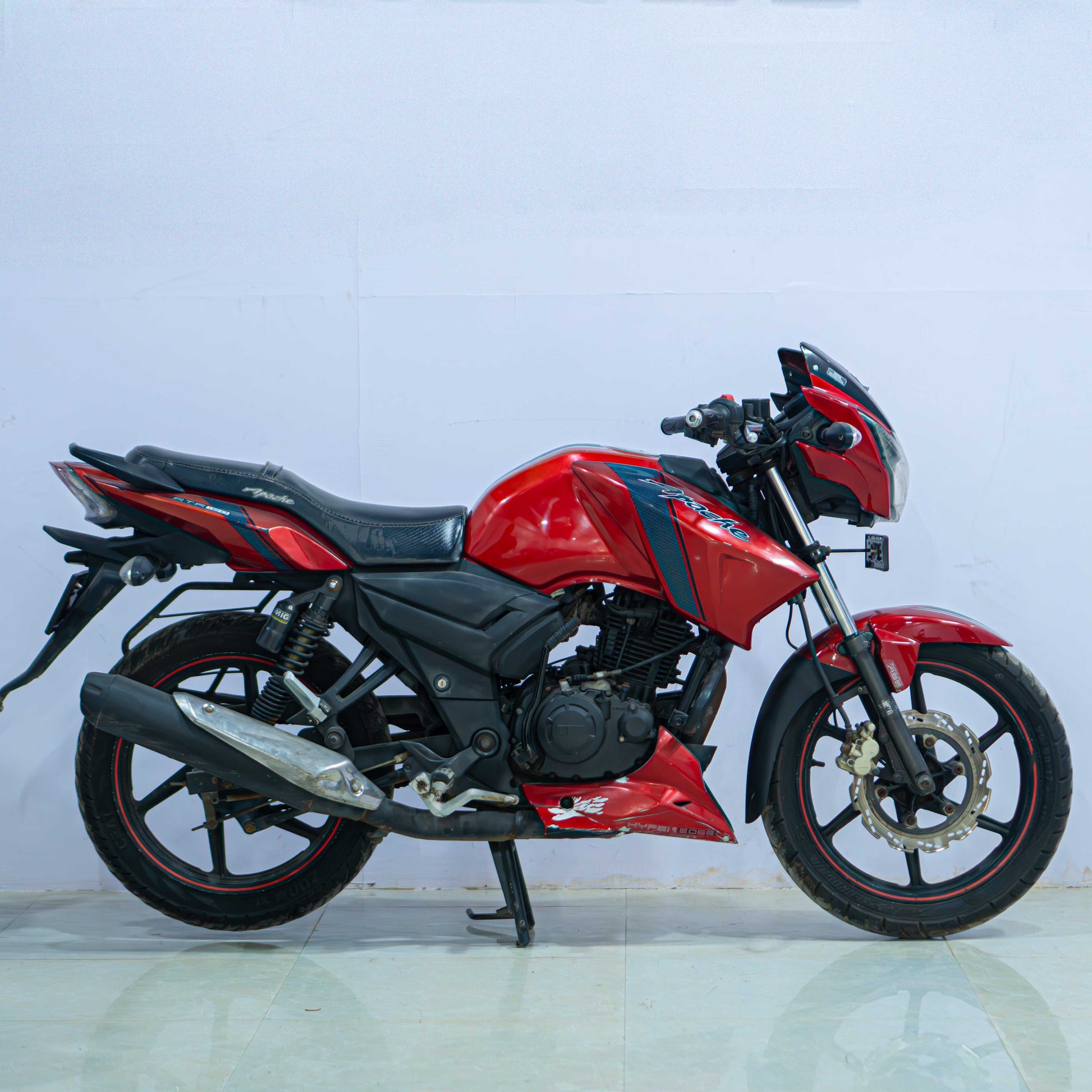 TVS Apache 160 motorcycle parked on a street, featuring sporty design and vibrant color scheme.