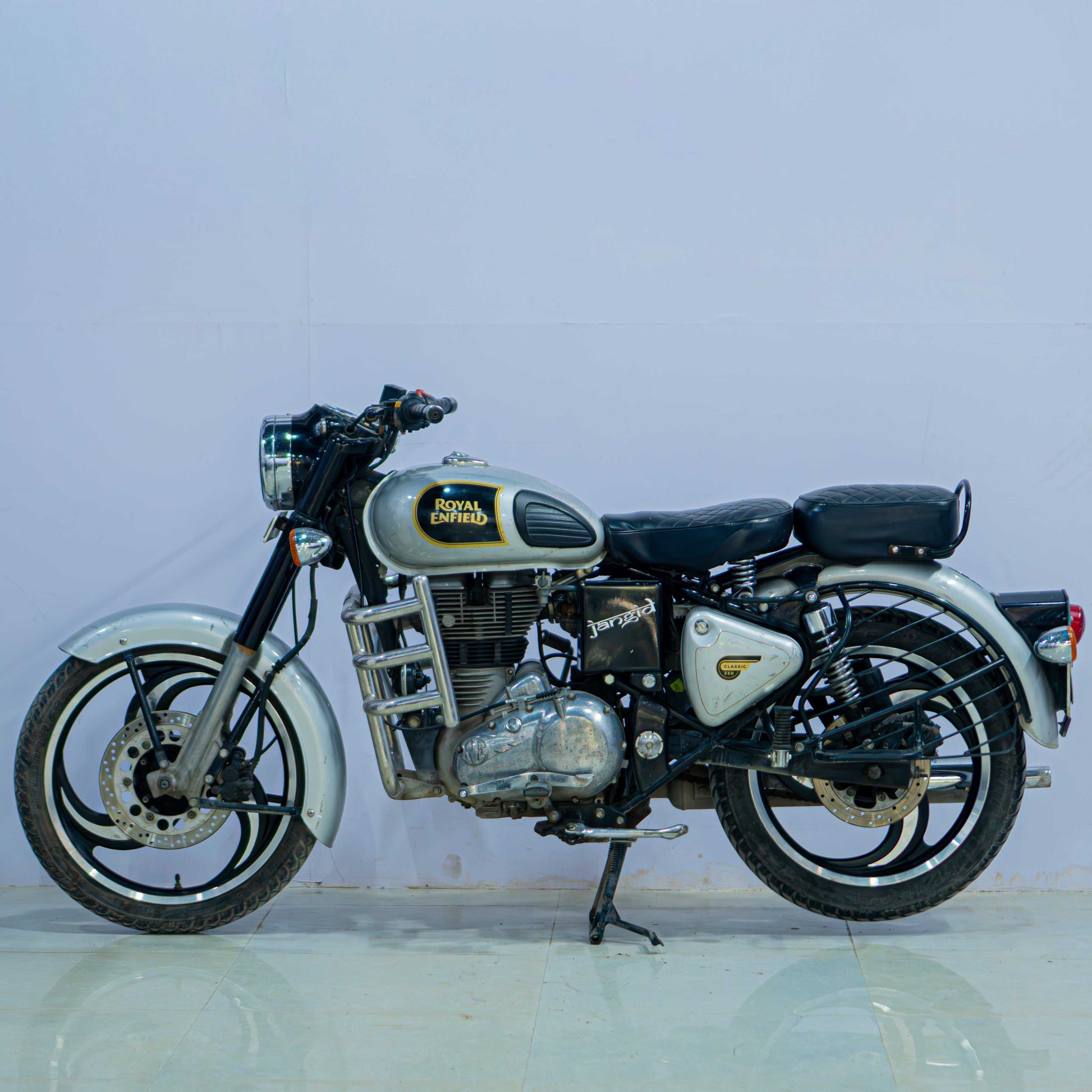Royal Enfield Classic 350 motorcycle with black fuel tank, chrome accents, and vintage styling, parked on a scenic road.