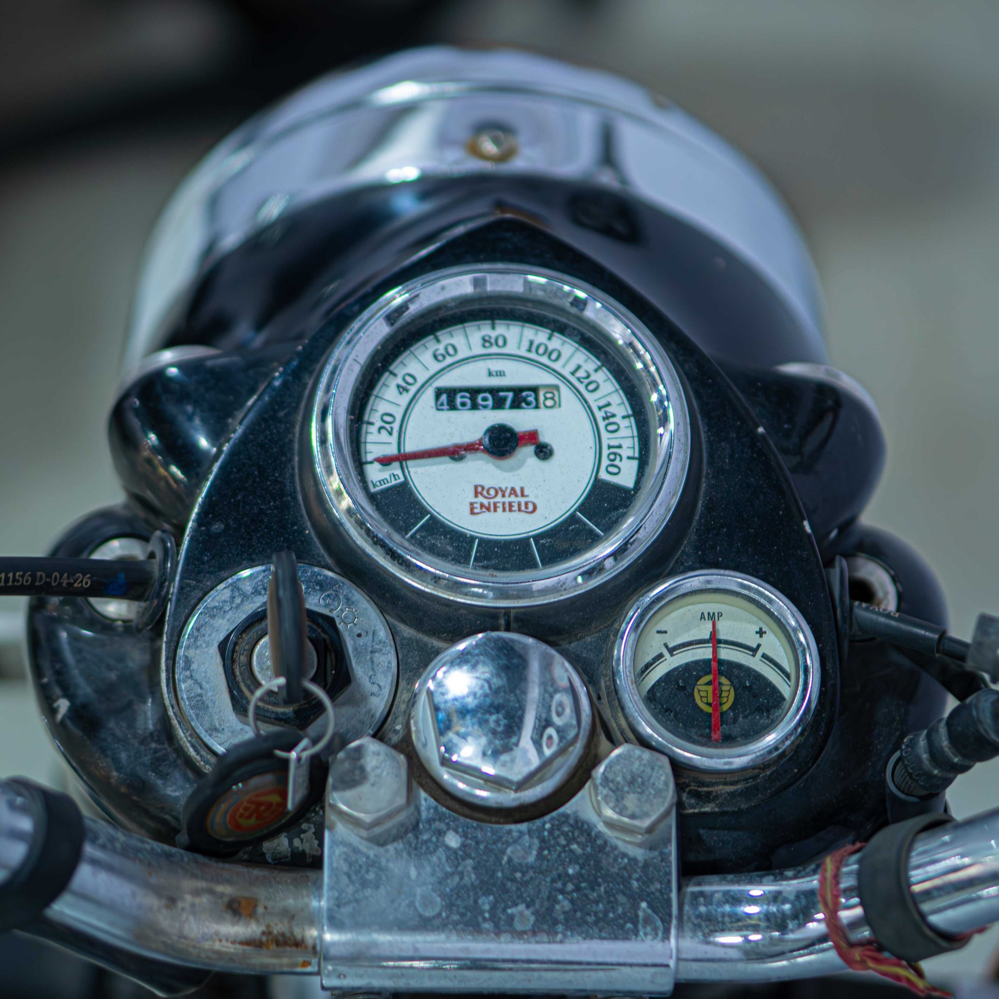 Royal Enfield Classic 350 motorcycle with black fuel tank, chrome accents, and vintage styling, parked on a rural road.