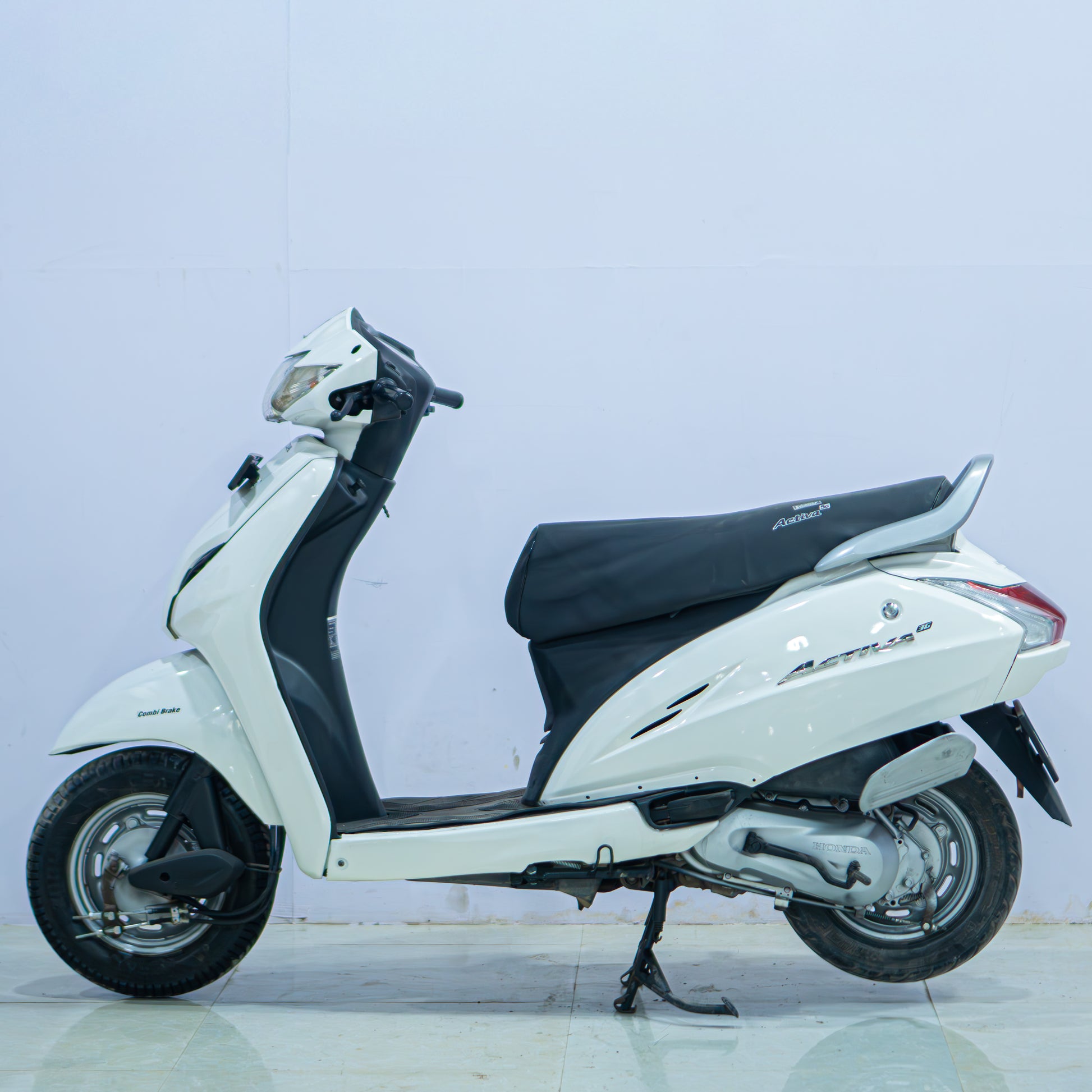 Honda Activa 3G scooter in blue with a sleek design and digital display, parked on a city street.