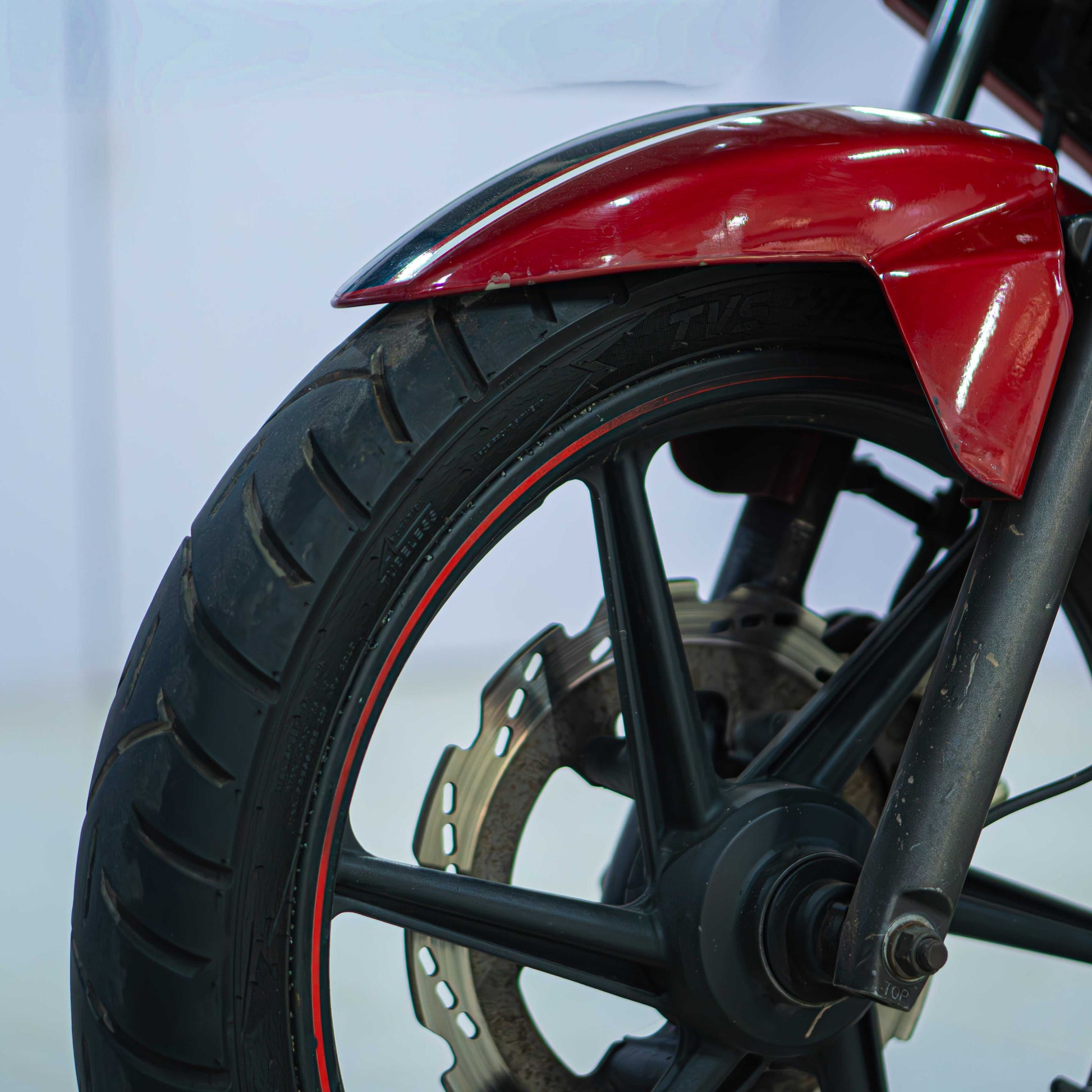 TVS Apache 160 motorcycle shown from the side with sporty design and black and red color scheme, featuring sleek bodywork and alloy wheels.