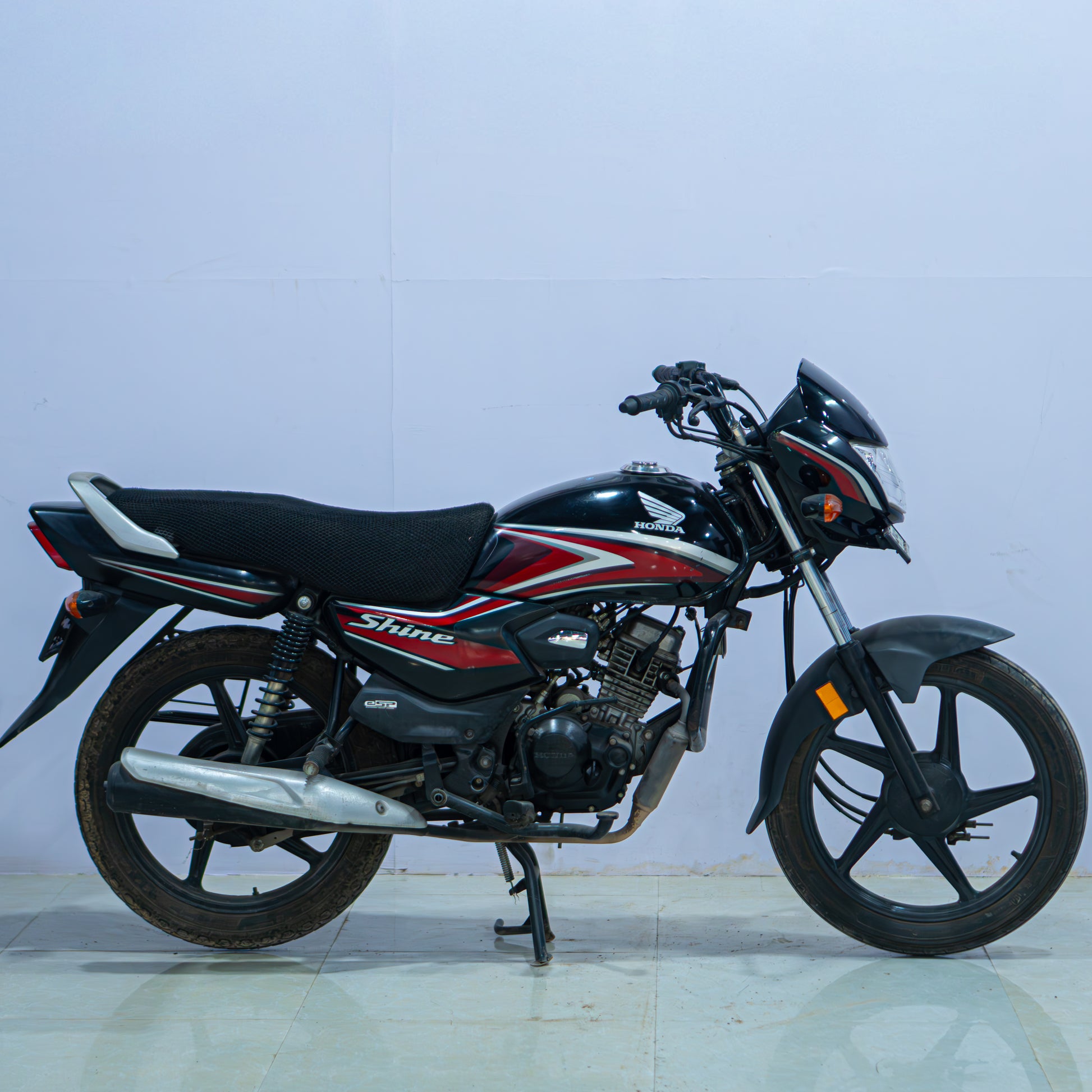 Honda Shine 100 motorcycle from BikeDilwado showing the front view with headlights and handlebar features.