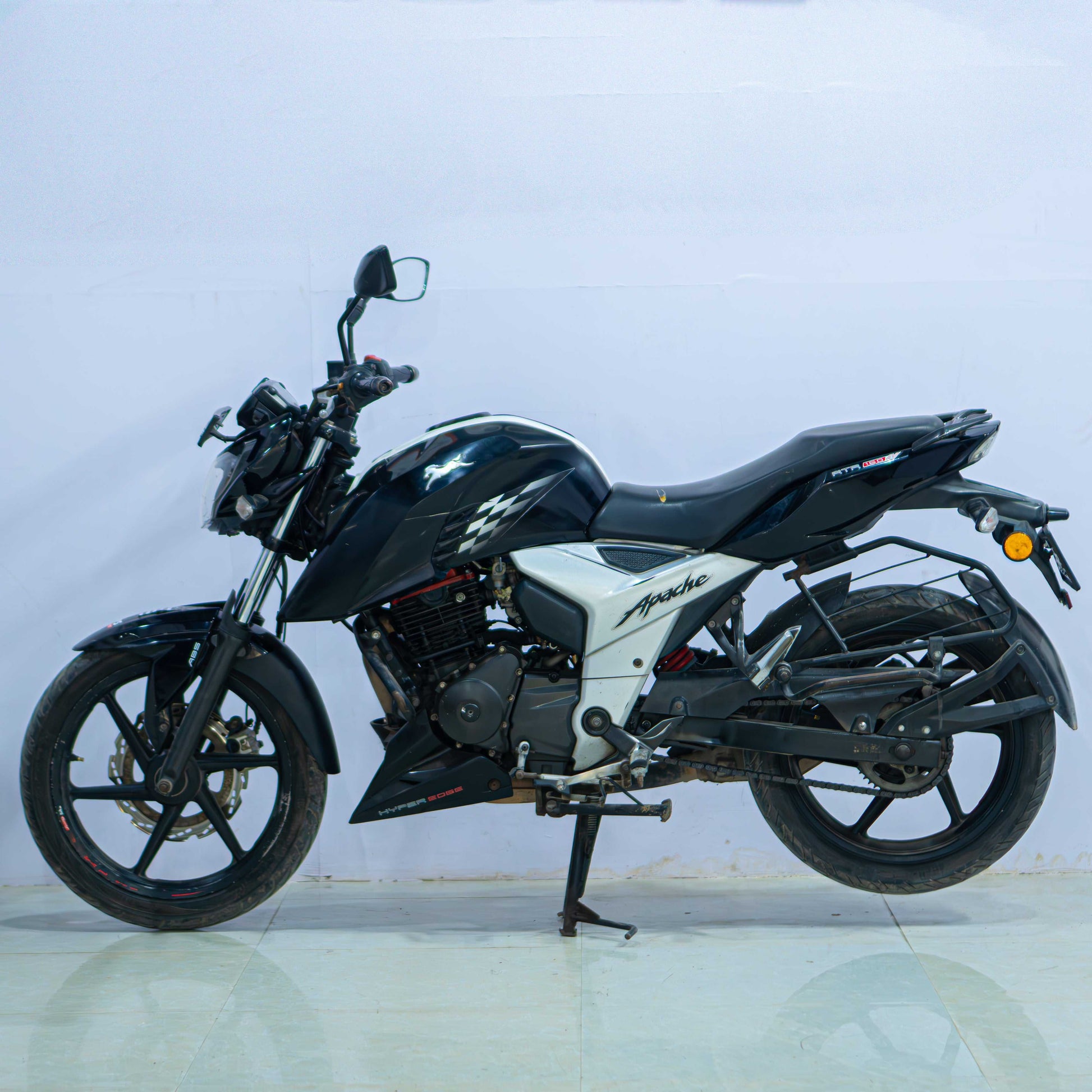 Red TVS Apache 160 4V motorcycle with sporty design and sleek body, parked on a city street.