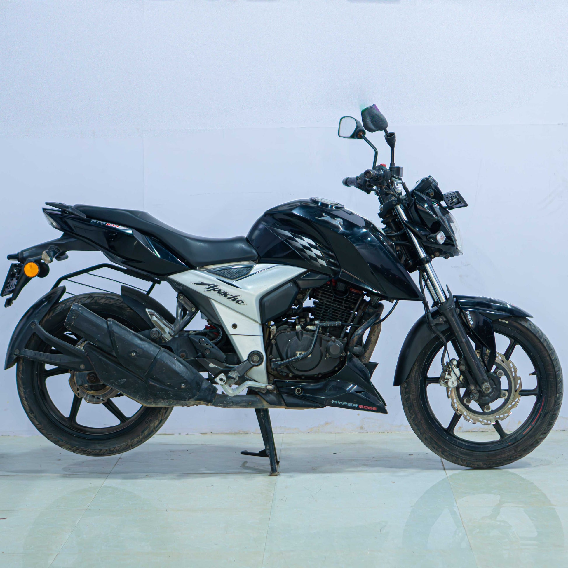 Red TVS Apache 160 4V motorcycle parked on a street, showcasing its sleek design and sporty look.