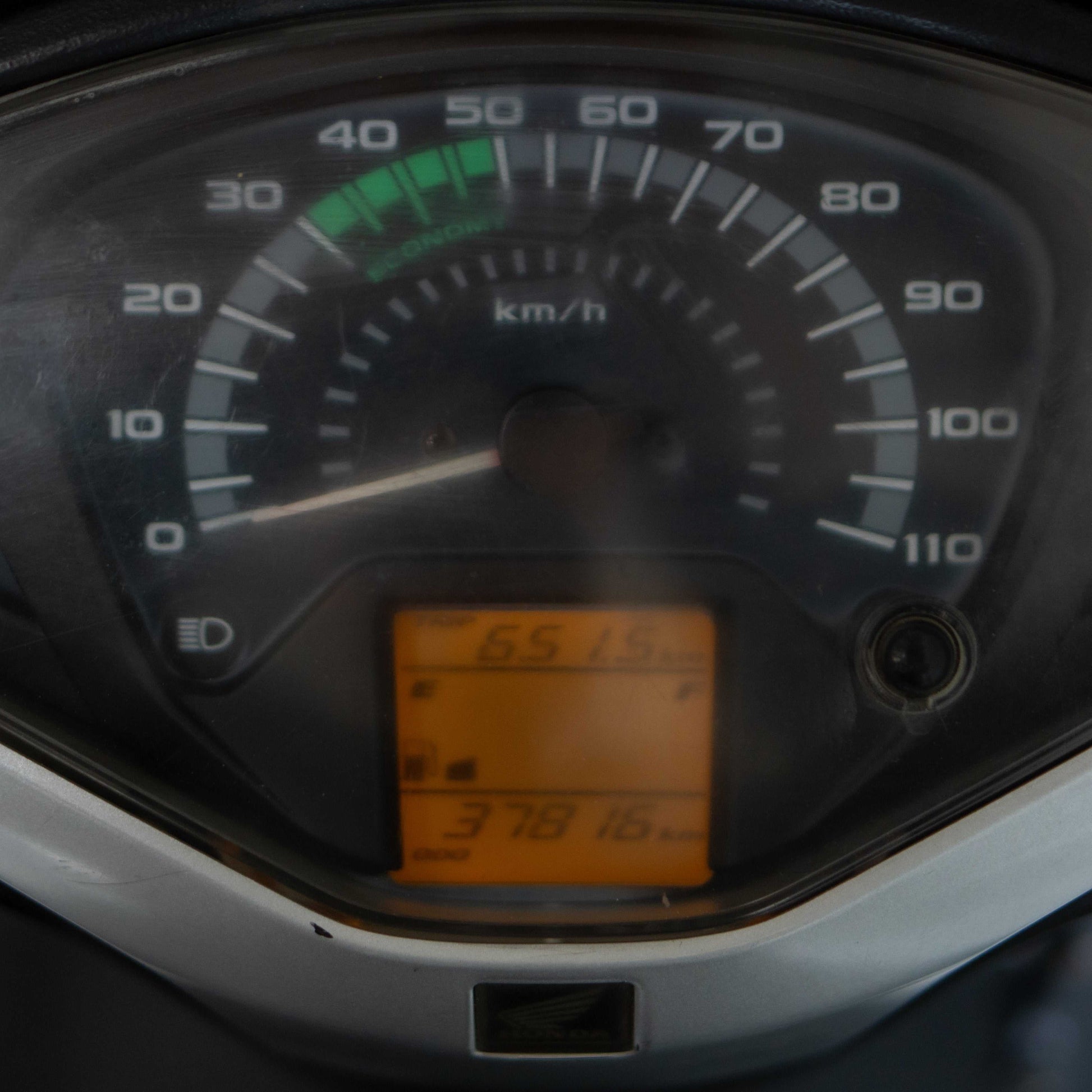 Close-up of a motorcycle speedometer with digital display showing speed and other metrics.