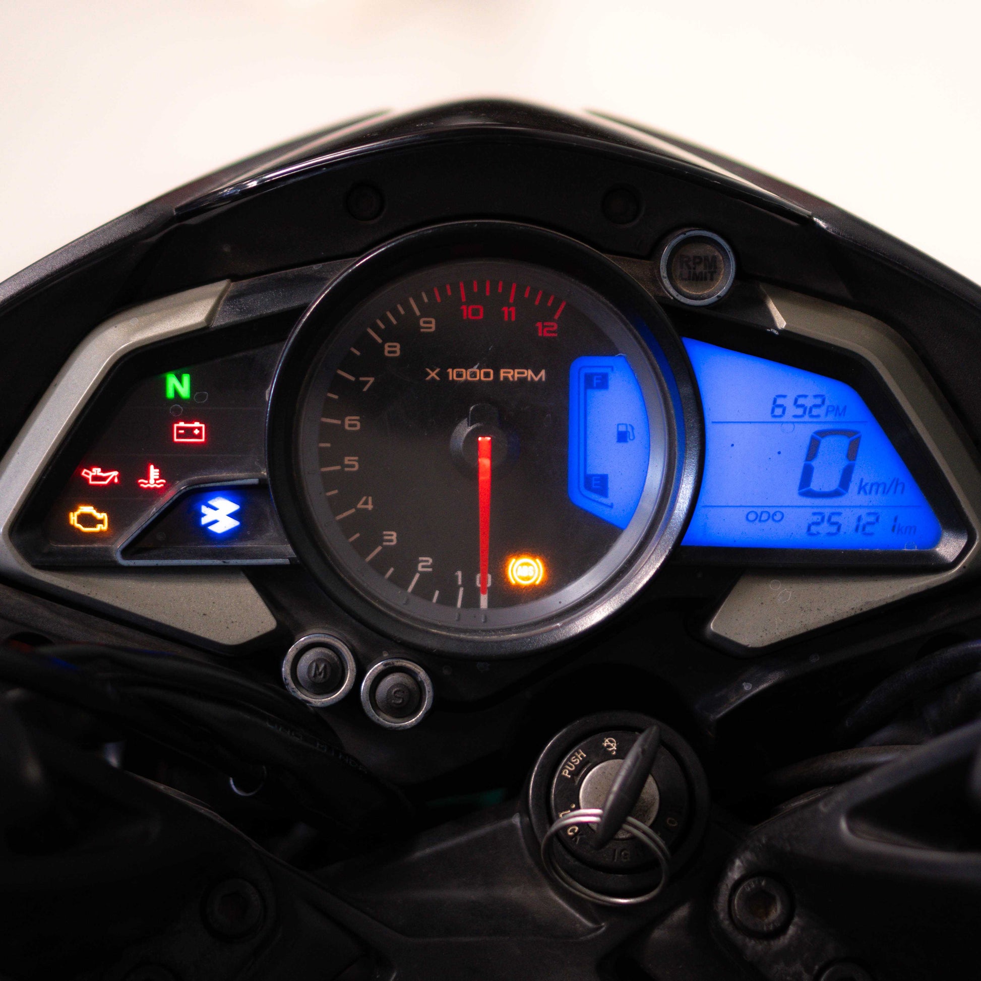 Close-up of a motorcycle dashboard with various indicators and gauges.