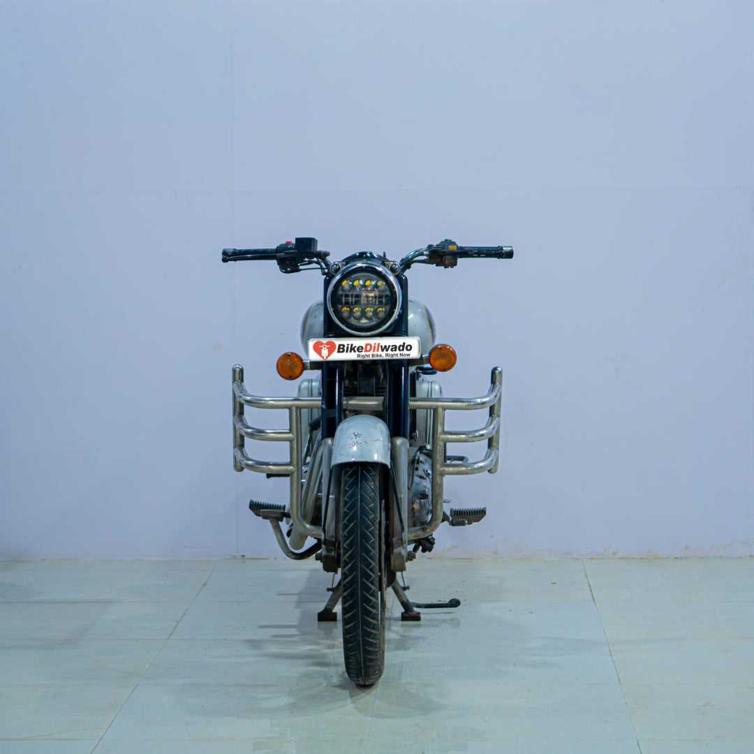 Royal Enfield Classic 350 motorcycle with black fuel tank, chrome accents, and vintage design, parked on a street.