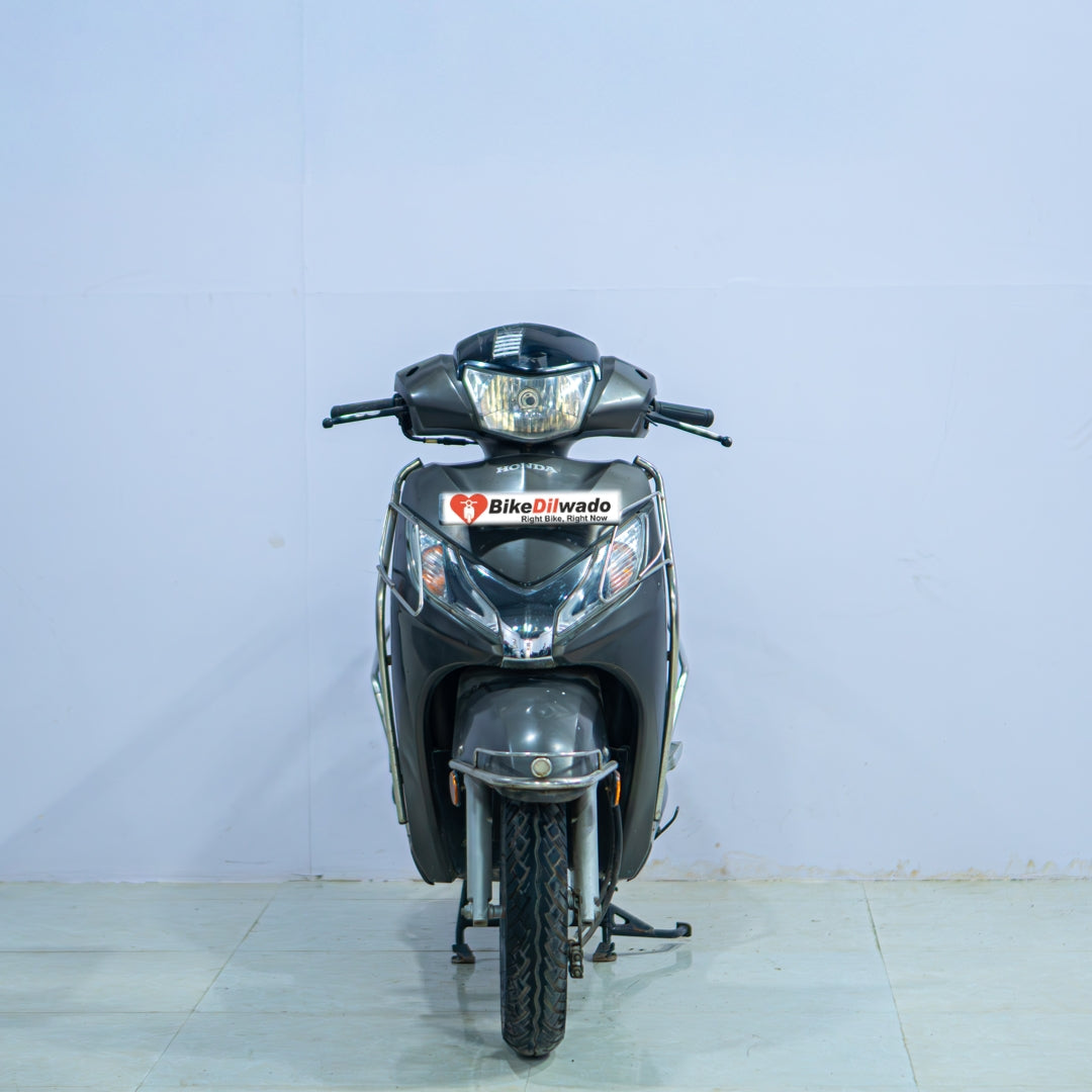 Honda Activa 125 scooter with black seat and silver body, displayed outdoors on a paved road.