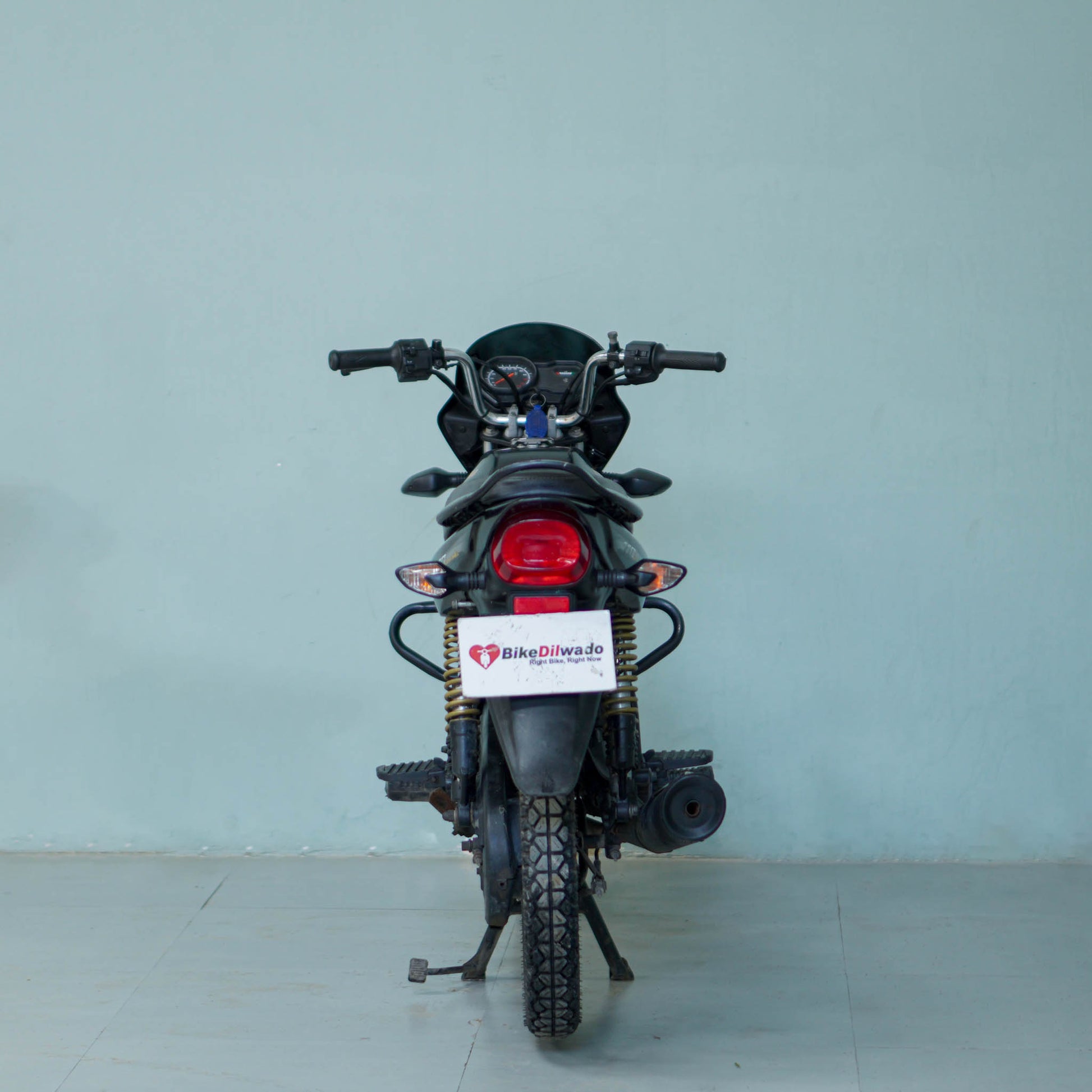 Bajaj Platina motorcycle with black and silver body, featuring a comfortable seat and sleek design, displayed on a stand.