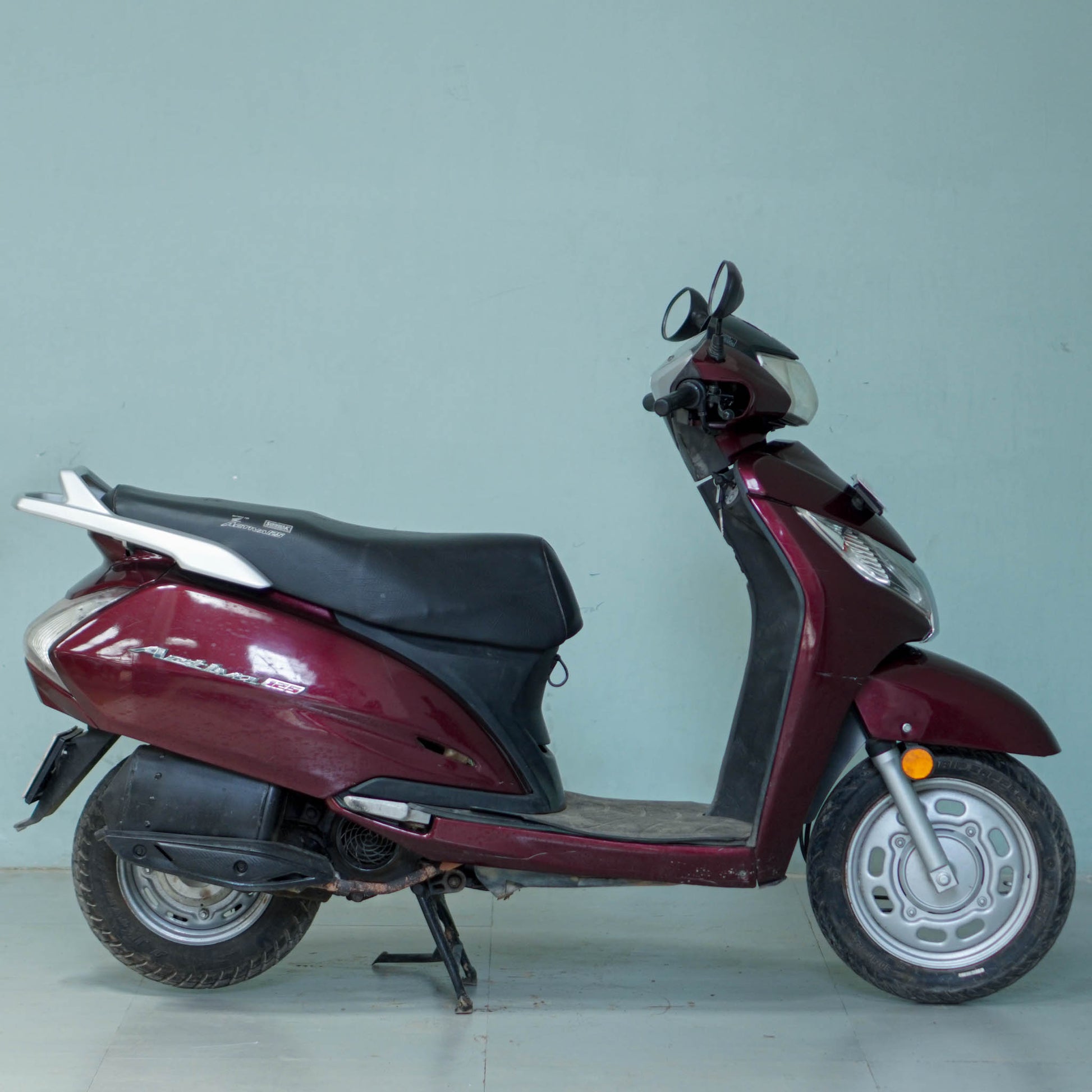 Honda Activa 125 scooter in black with chrome accents, shown from side view on a city street.