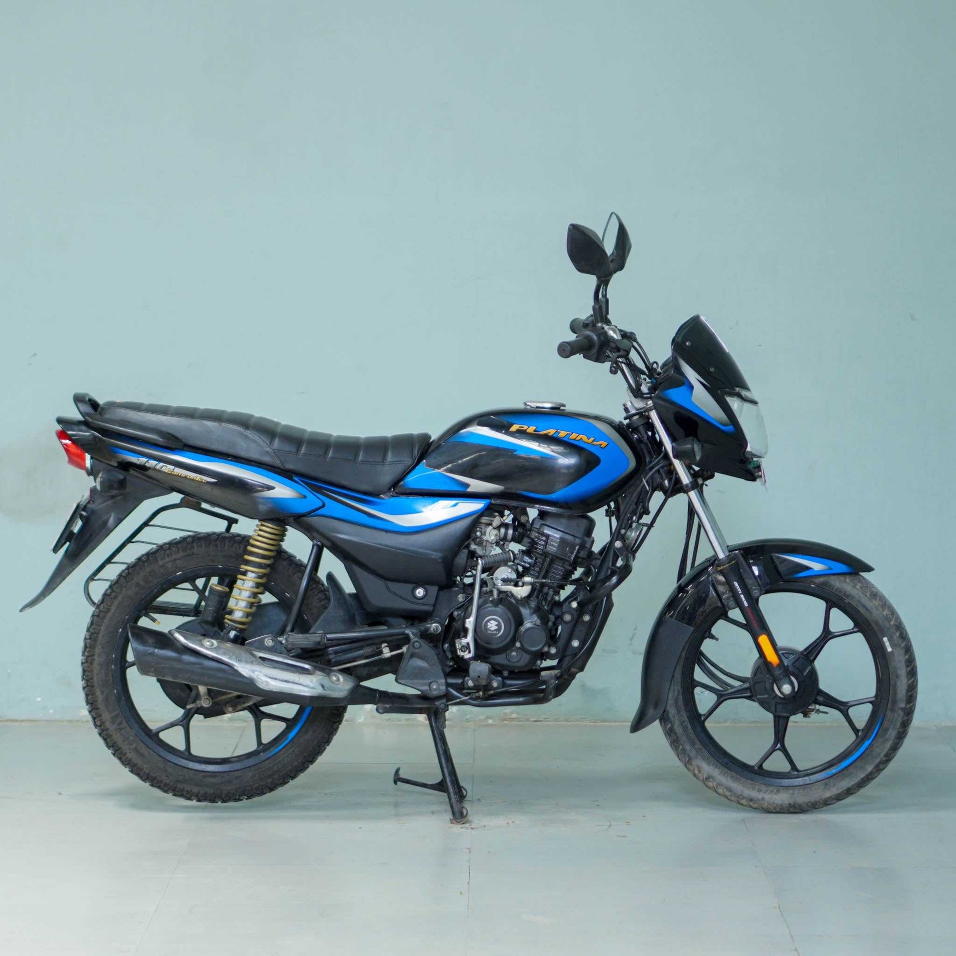 Bajaj Platina motorcycle with black and silver body, featuring sleek design and comfortable seating, parked on a city street.