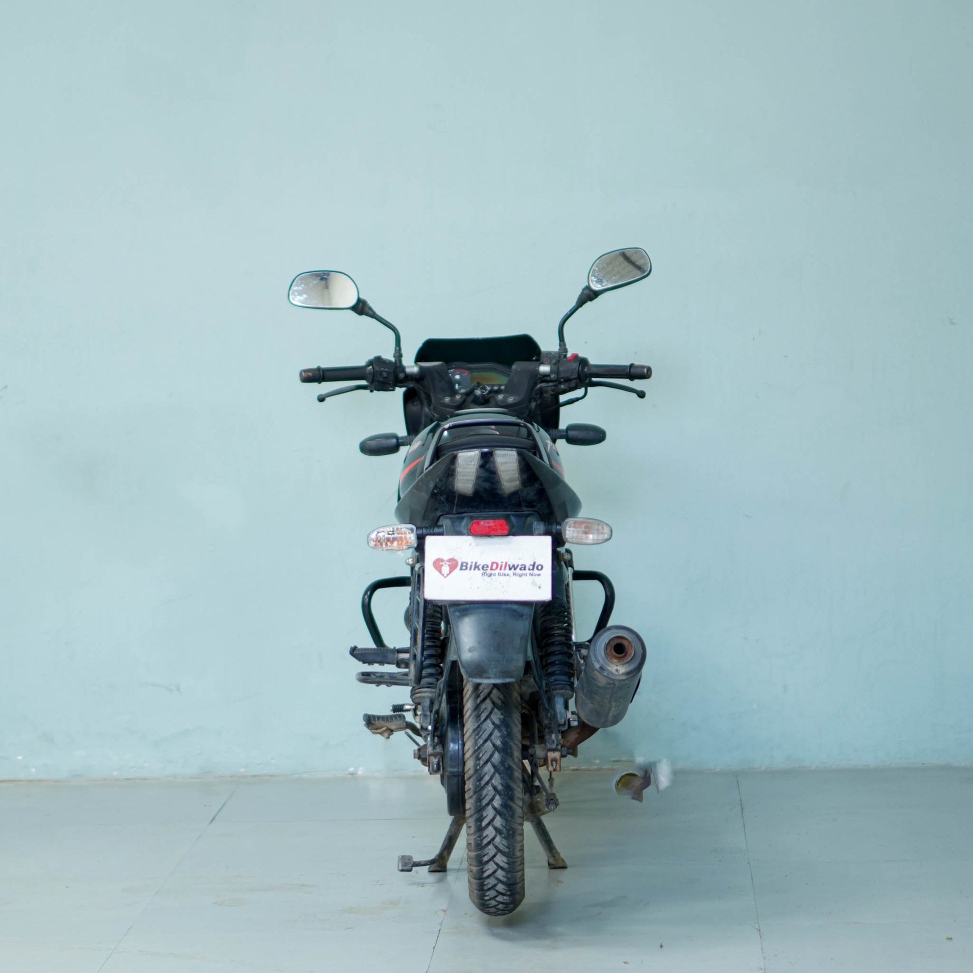 Black Bajaj Pulsar 125 motorcycle with sporty design and chrome accents, parked on a city street.