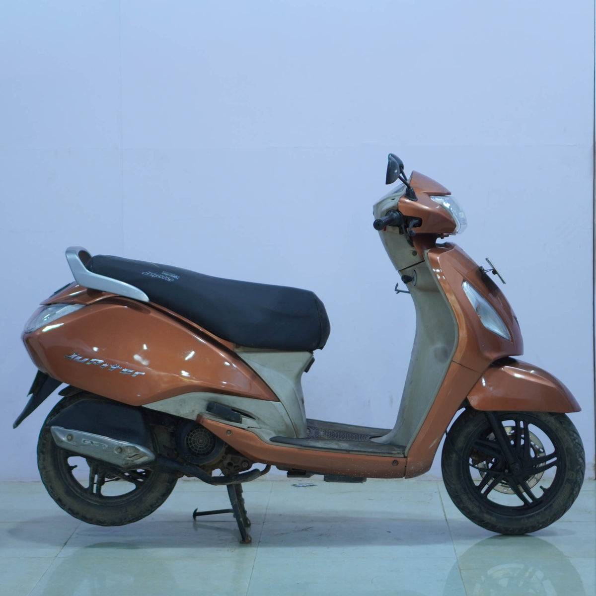 Silver TVS Jupiter 125 scooter with black seat and alloy wheels, parked on a city street.