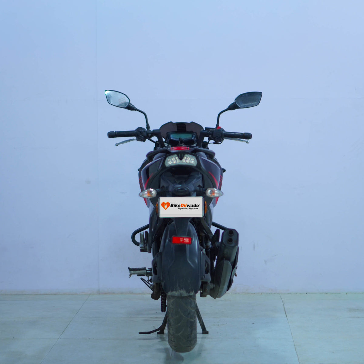 TVS Apache 200 4V motorcycle displayed on a stand with a sleek black and red design, showcasing its sporty appearance and modern features.
