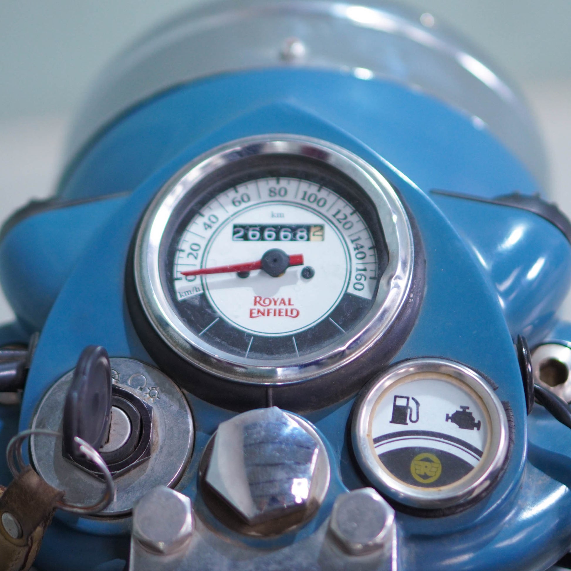 Royal Enfield Classic 500 motorcycle with chrome accents and vintage design, parked on a road with a scenic background.