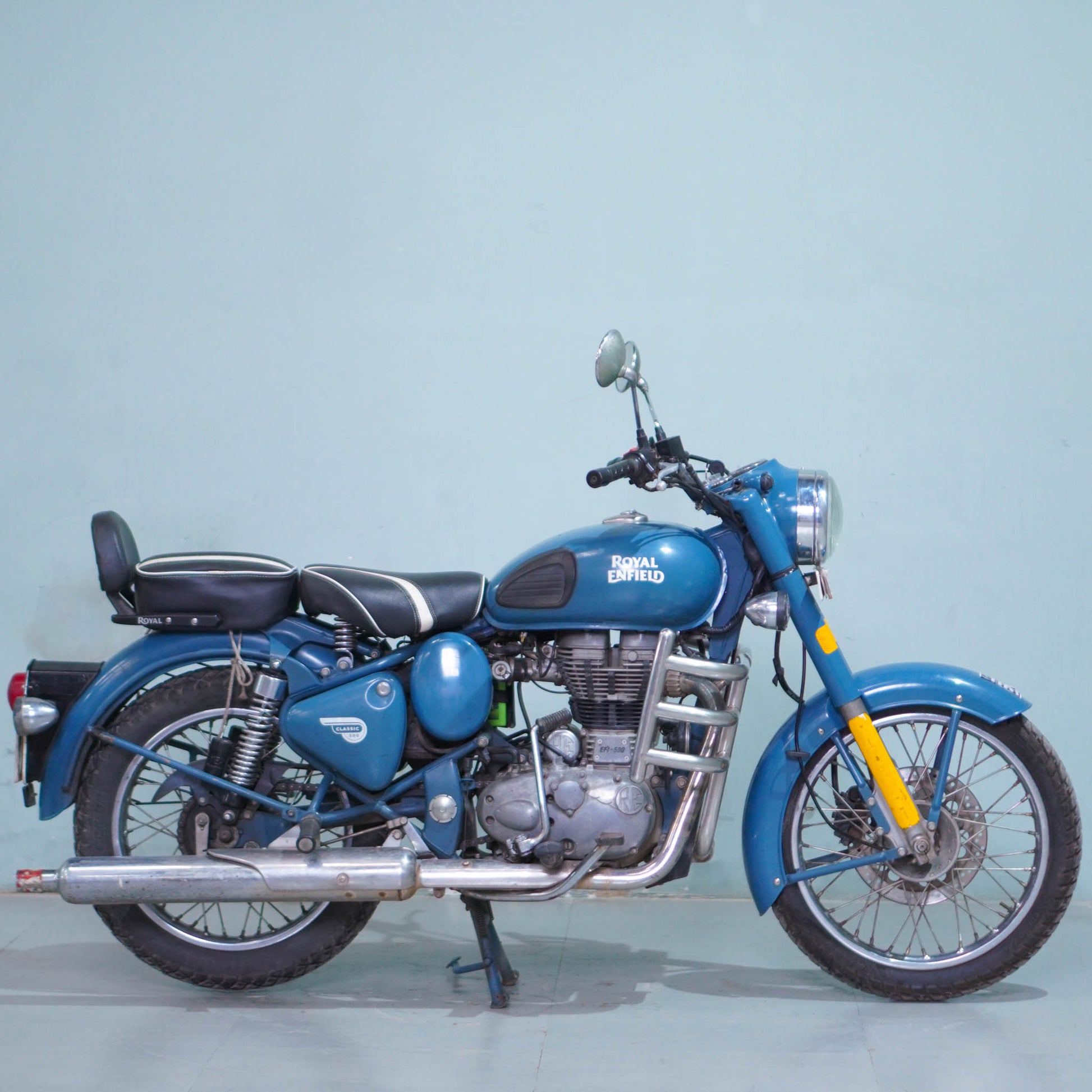 Royal Enfield Classic 500 motorcycle with black fuel tank and chrome accents, parked on a city street.