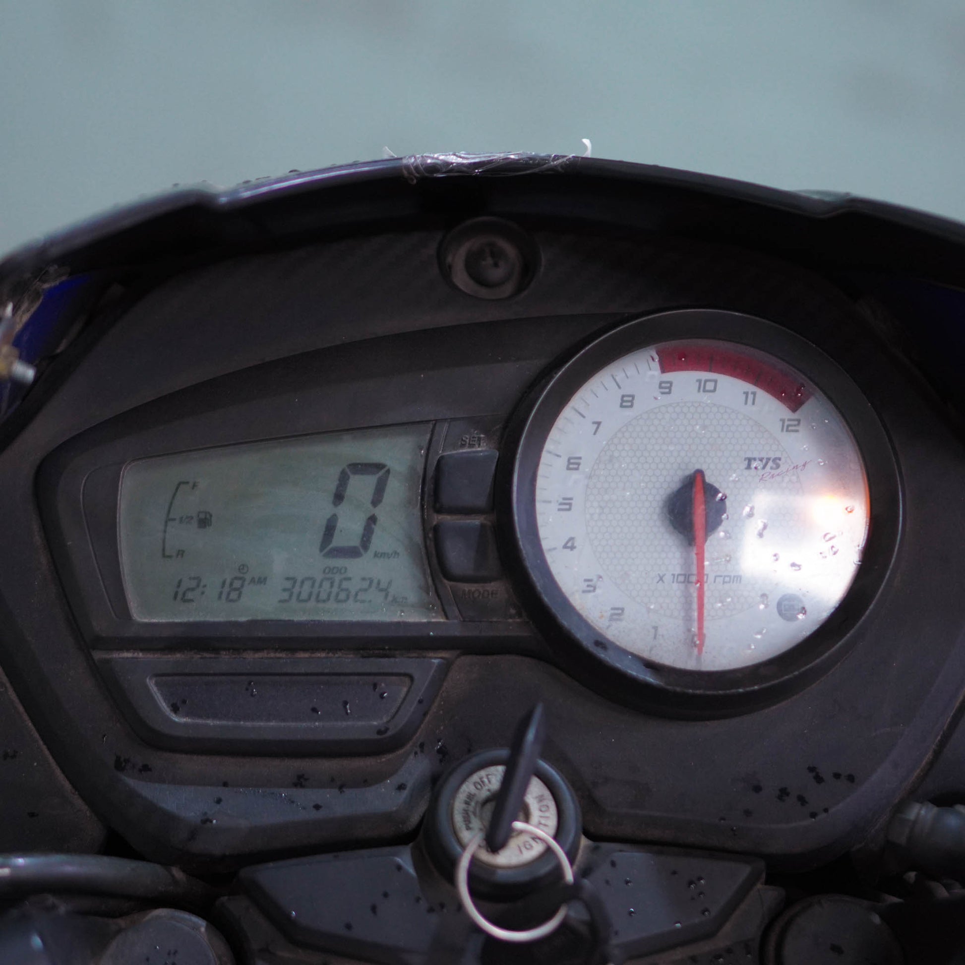 TVS Apache 160 motorcycle parked on a road, showcasing its sporty design and vibrant color scheme.