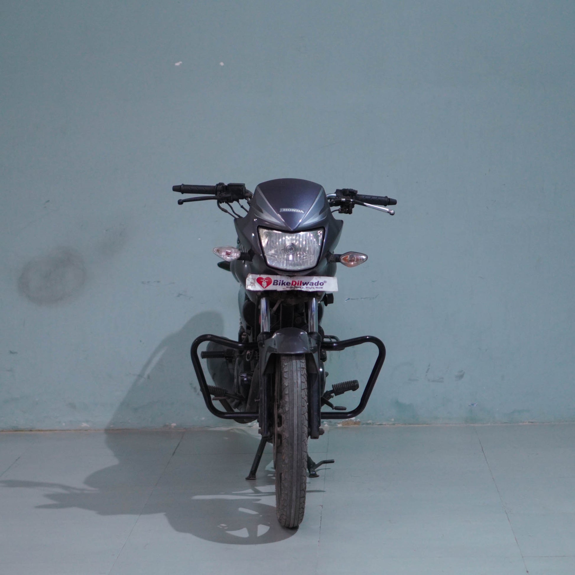 Honda Shine 125 motorcycle from BikeDilwado with a sleek black and chrome finish, showing the front view of the bike.